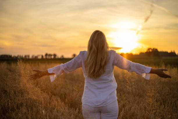 istock Woman with raised arms facing the beautiful sunset 1357000581