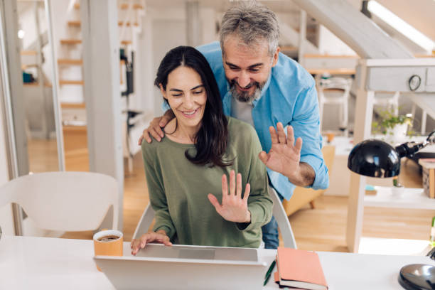 istock Mature woman working online and her husband helping her 1357001748