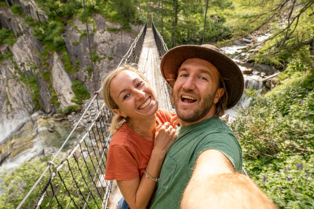 istock Young couple taking selfies on a hanging bridge wile on a hike 1357003118