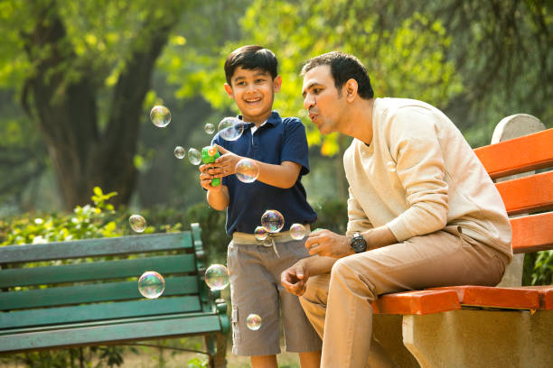 ojciec i syn bawiący się pistoletem bąbelkowym w parku - bubble wand child blowing asian ethnicity zdjęcia i obrazy z banku zdjęć