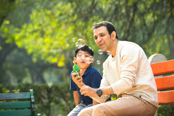 istock Father and son playing with bubble gun at park 1357004809