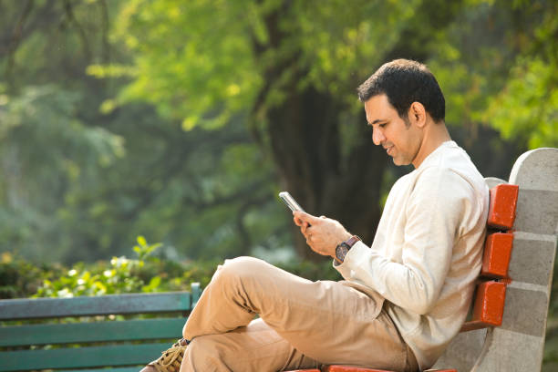 istock Mid adult man using mobile phone at park 1357004887