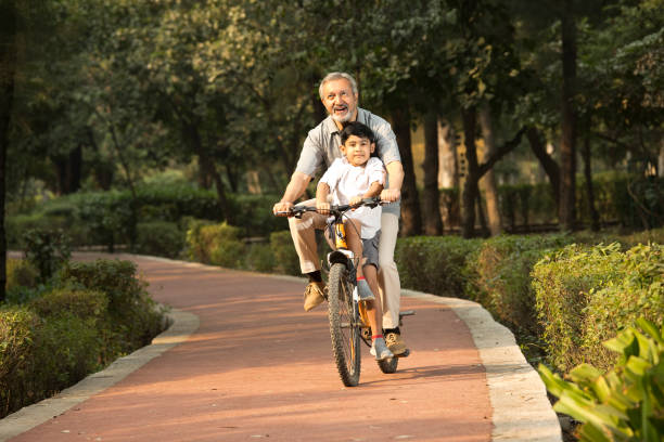 istock Grandfather with grandson riding bicycle at park 1357005151
