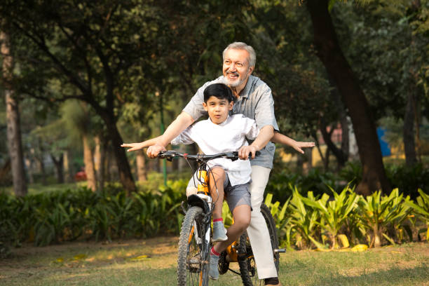 istock Grandfather with grandson riding bicycle at park 1357005177