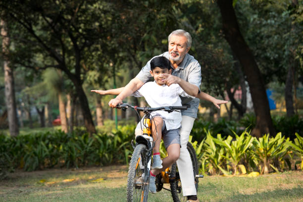 istock Grandfather with grandson riding bicycle at park 1357005234