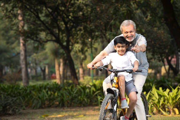 istock Grandfather with grandson riding bicycle at park 1357005334