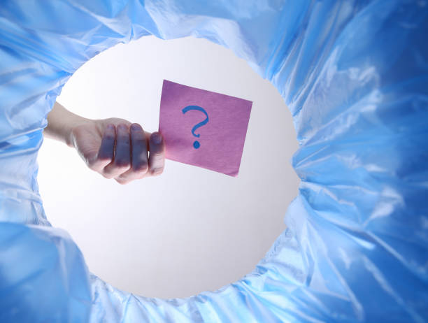 Hand throws piece of paper with question mark into trash bin with package. Inside view
