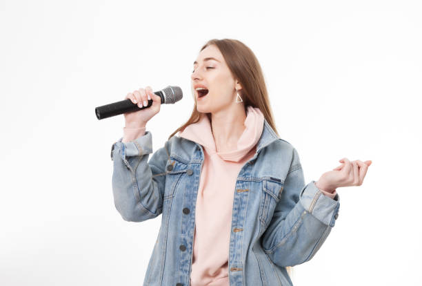 istock Young cheerful caucasian woman singing into microphone isolated on white background 1357011103