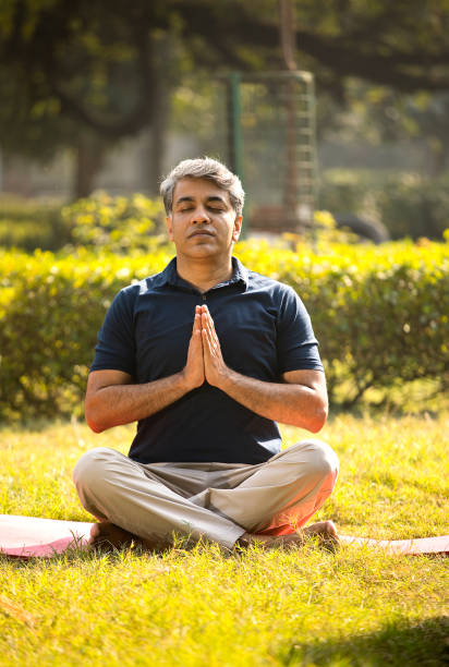 istock Man sitting in lotus position and meditating at park 1357012179