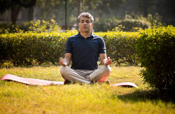 istock Man sitting in lotus position and meditating at park 1357012189