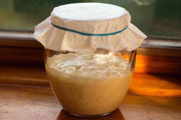 Sourdough starter on window ledge. Close-up of sourdough starter sitting on window ledge.  Active fermentation present. yeast starter stock pictures, royalty-free photos & images