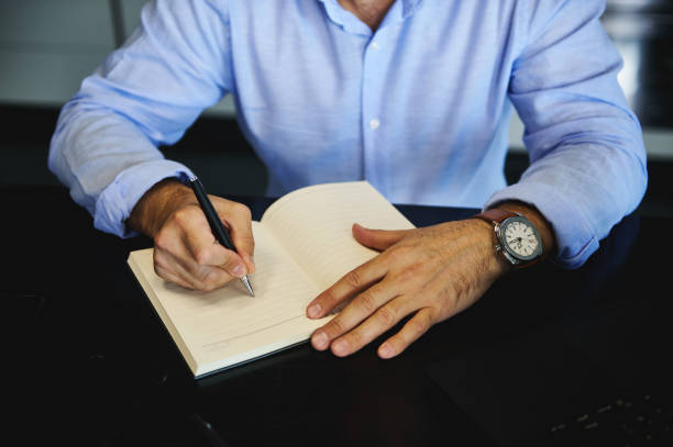 istock Cropped view of a middle-aged European man writing in a notebook, planning projects, and making notes in a diary. 1357013511