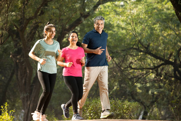 Happy family jogging at park Happy daughter with parents jogging at park indian man walking in park stock pictures, royalty-free photos & images