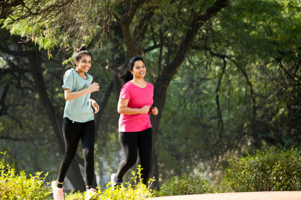 Mother and daughter jogging at park stock photo