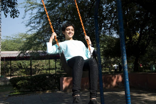 istock Happy girl sitting on swing at park 1357016289