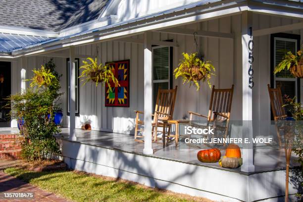 Hanging Ferns Wooden Rocking Chairs Colorful Art And A Collection Of Pumpkins Create An Inviting Seasonal Look For The Front Porch Of A Renovated Woodframe House In Historic White Springs Florida Stock Photo - Download Image Now
