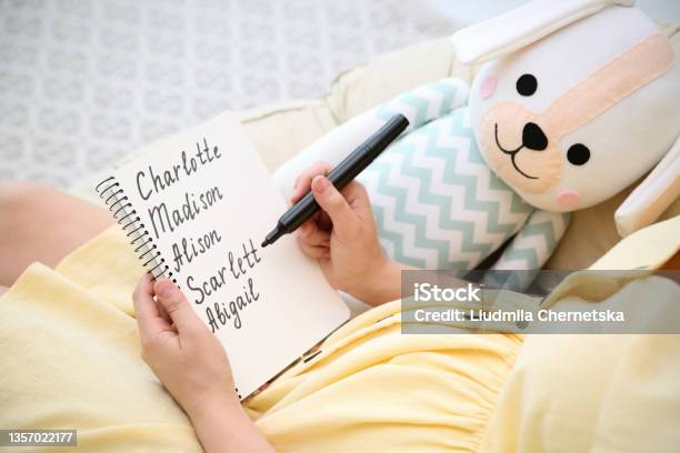Pregnant Woman With Baby Names List Sitting In Armchair Closeup Stock Photo - Download Image Now