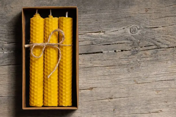 Photo of Yellow beeswax candles in a cardboard box, top view. Copy space for text.