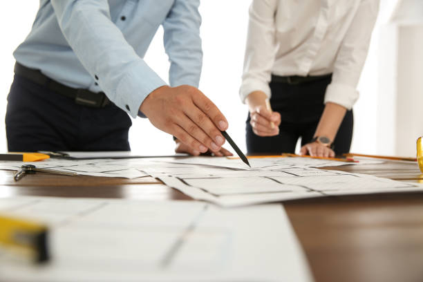 istock People working with construction drawings at table, closeup 1357023296
