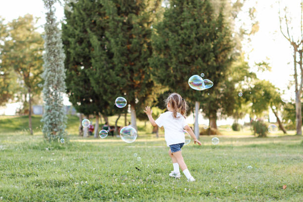 istock Cute little girl outdoors blowing bubbles 1357024023