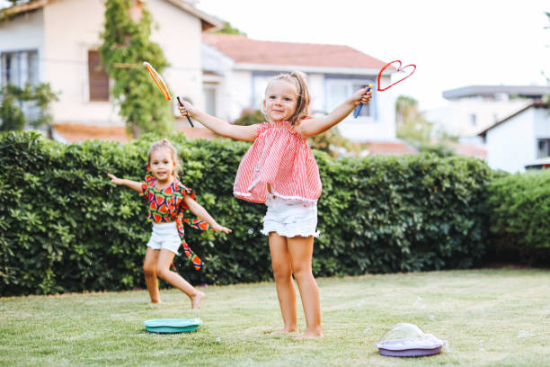 istock Cute little girls outdoors blowing bubbles 1357024194