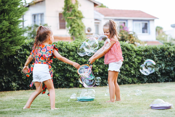 istock Cute little girls outdoors blowing bubbles 1357024872
