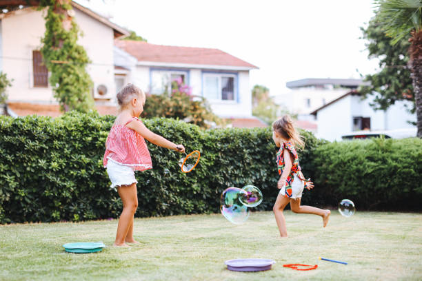 istock Cute little girls outdoors blowing bubbles 1357024889