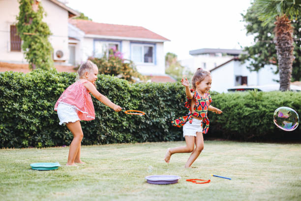 istock Cute little girls outdoors blowing bubbles 1357024993