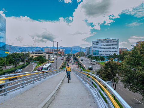 Bogota, Colombia - November 27, 2021: A high angle view of the bridges on Avenida Esperanza, also called Calle 24 or Avenida Luis Carlos Galán, at the point where the Avenida Esperanza goes over Avenida 68. Between the two West and Eastbound bridges is the footbridge combined with bicycle lanes. In the far background are the Andes Mountains. The altitude at street level is 8,660 feet above mean sea level. Image shot on mobile phone, on a fairly clear day with blue skies and white clouds.