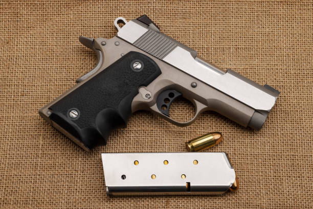 istock .45 automatic handgun with bullet magazine on burlap background , Classic gun 1357038175