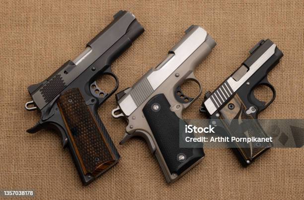 Semi Automatic Handguns On Burlap Background 1911 The Same Of Single Action Stock Photo - Download Image Now