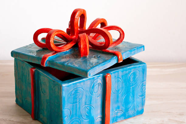 Blue Christmas Present tied with Red Ribbon Decorative Ceramic Piece on a White Background stock photo