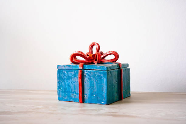 Blue Christmas Present tied with Red Ribbon Decorative Ceramic Piece on a White Background stock photo