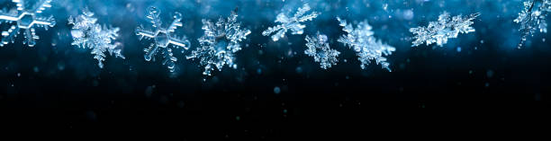 Cold winter snowflakes falling with sparkling falling snow and glittering blue background. Cold winter snowflakes falling with sparkling falling snow and glittering blue background. ice crystal photos stock pictures, royalty-free photos & images