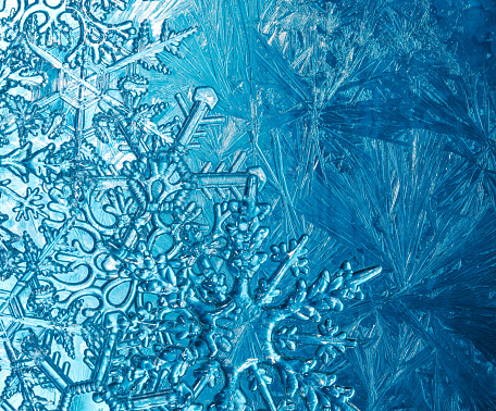 Wintry background with winter frost covered window with a pattern of ice crystals and clear snowflakes.