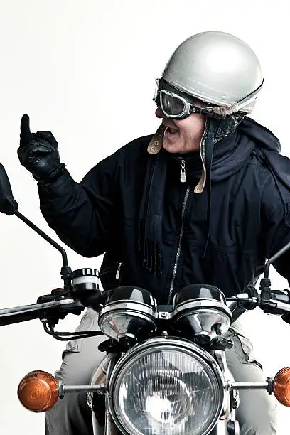 man drive his motorcycle with helmet and glasses making the finger.