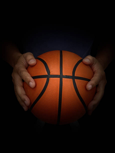 istock Basketball player holding a ball against black background 1357050068