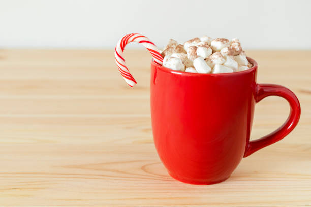 istock Cocoa in red mug with marshmallows and candy cane on table. Holiday drink, hot chocolate 1357054750