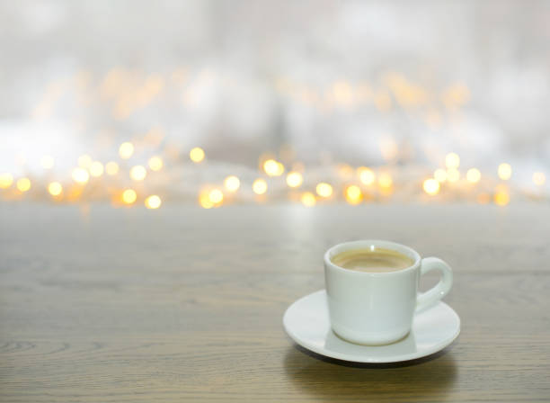 a cup of coffee on the table in a cafe, a blurry light background with golden bokeh. evening coffee. winter, new year or christmas hot warming drink. a cup of black coffee, espresso. coffee time - julfika bildbanksfoton och bilder