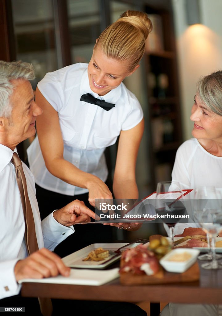 What would you recommend? Young waitress advises a mature couple on what to order at a smart restaurant Restaurant Stock Photo