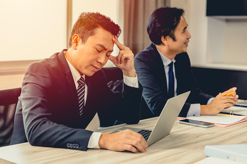 Businessman feel Tired Exhausted Headache with happy friend in business meeting room.