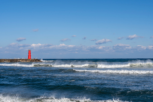 red lighthouse and raging waves