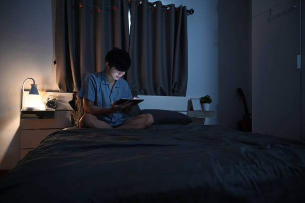 istock Young man in pajamas sitting in his comfortable bed and using digital tablet. 1357064781