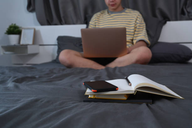 istock Daily planner on bed with blurred young man using laptop in comfortable bedroom. 1357064784