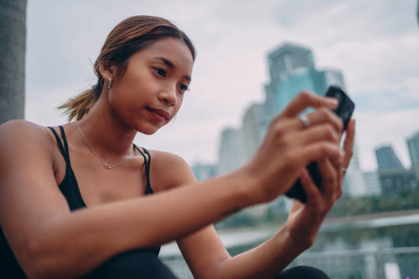 istock Female athlete using phone in a city park 1357068237