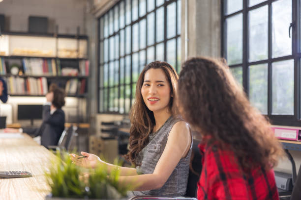 istock While working in the workplace, two lovely female coworkers interact. 1357069952