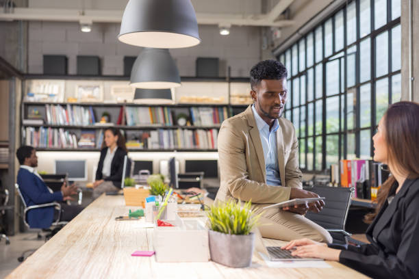 istock Colleagues in a boardroom discussion, seated at a table together, swapping ideas and strategizing project strategy. In the office, young business professionals 1357070502