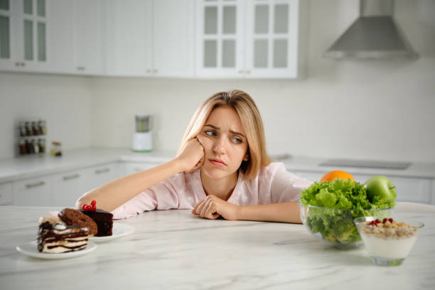 istock Woman choosing between sweets and healthy food at white table in kitchen 1357071022