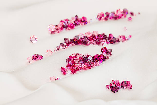 Diamond (ruby) stones heap over cream silk cloth stock photo