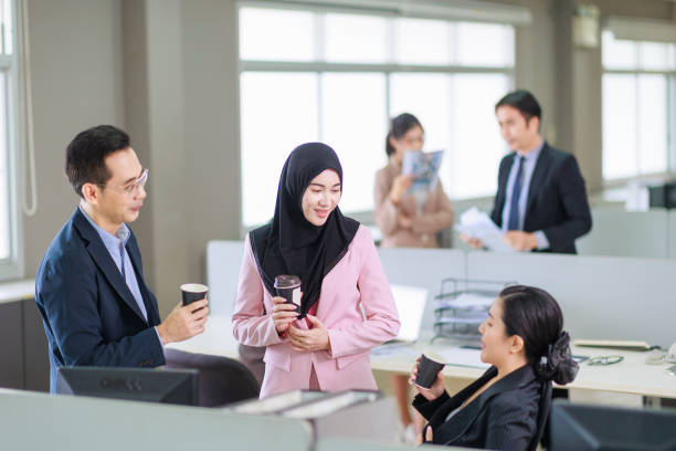 istock Asian officer talking with their coworker in the office while having a coffee break. 1357072975